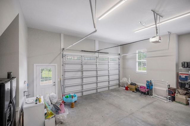 garage featuring washer / dryer, black fridge, and a garage door opener