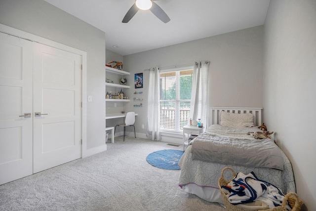 carpeted bedroom featuring a closet, ceiling fan, and built in desk