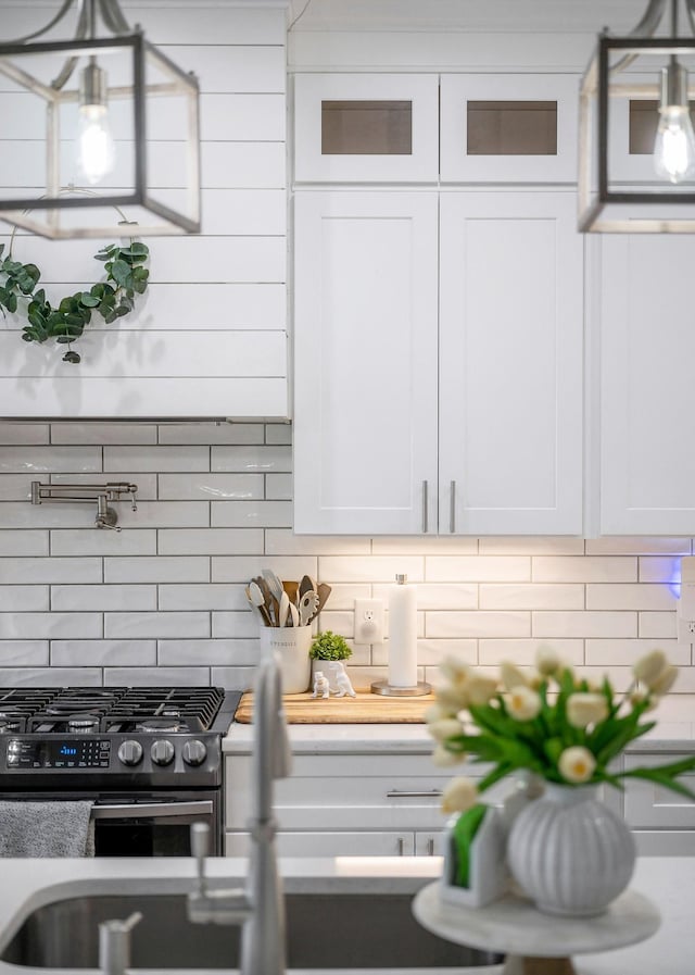 kitchen featuring white cabinets, decorative backsplash, and stainless steel gas range oven