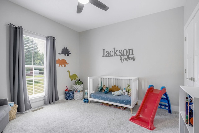 bedroom with ceiling fan, carpet floors, and a crib