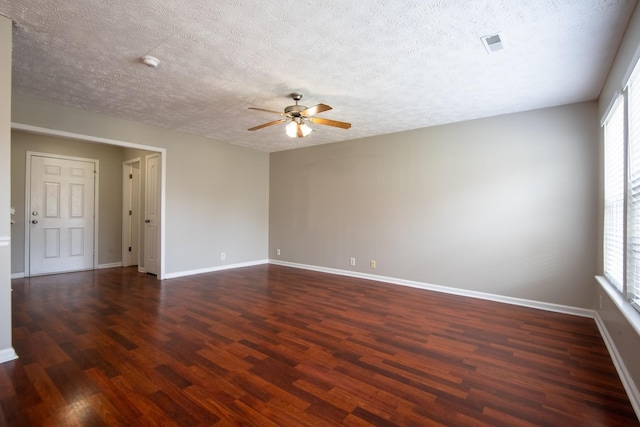 empty room with a textured ceiling, ceiling fan, and dark hardwood / wood-style floors