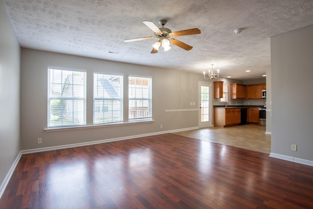 unfurnished living room featuring ceiling fan with notable chandelier, dark hardwood / wood-style flooring, and sink