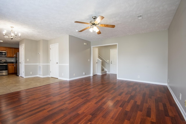 unfurnished living room featuring a textured ceiling, dark wood-type flooring, and ceiling fan with notable chandelier