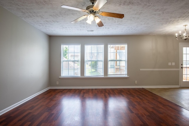 empty room with ceiling fan with notable chandelier, a textured ceiling, and dark wood-type flooring