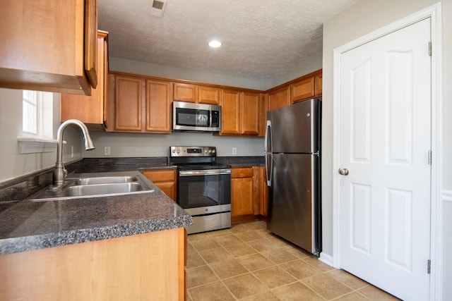 kitchen featuring stainless steel appliances, a textured ceiling, and sink