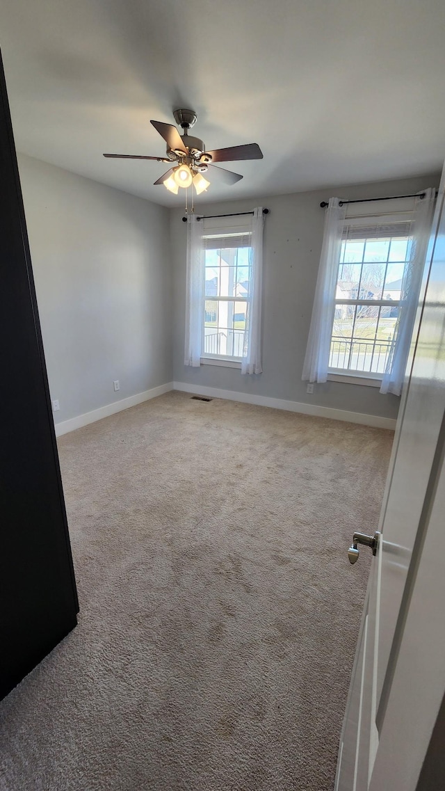 empty room featuring ceiling fan and carpet