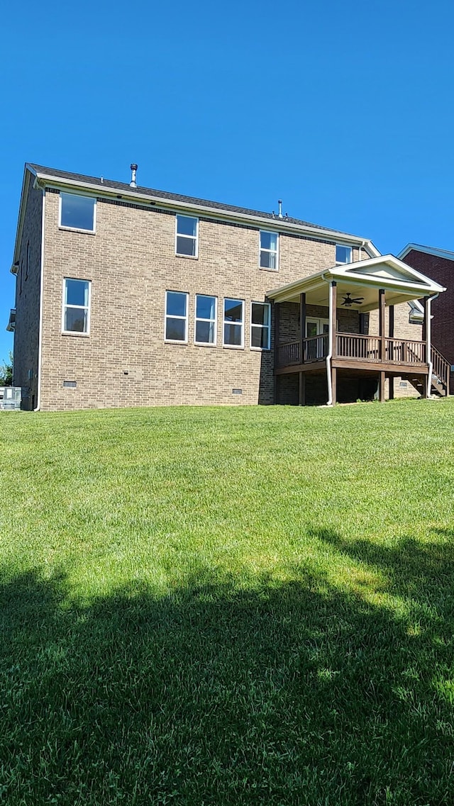 back of property with ceiling fan, a yard, and central AC unit