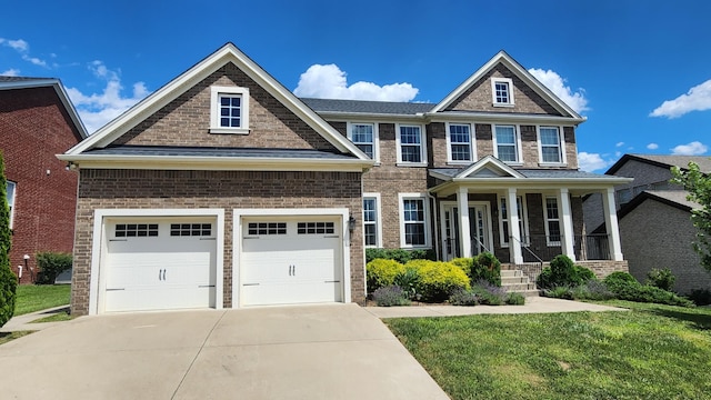 craftsman house with covered porch, a garage, and a front lawn