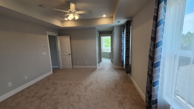 carpeted empty room featuring ceiling fan and a tray ceiling