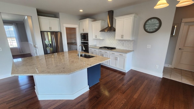 kitchen with appliances with stainless steel finishes, white cabinetry, a kitchen island with sink, and wall chimney exhaust hood