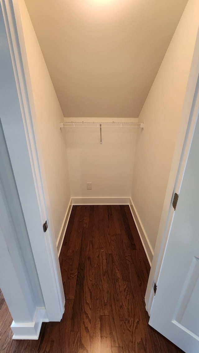 spacious closet with dark hardwood / wood-style flooring and vaulted ceiling