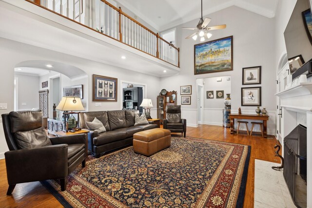 living room featuring high vaulted ceiling, ceiling fan, a high end fireplace, and light hardwood / wood-style floors