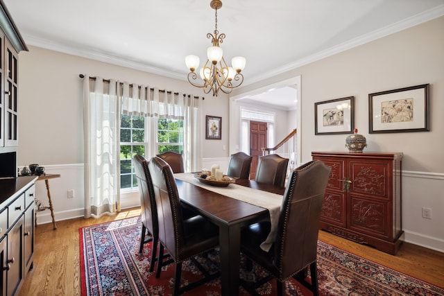 dining area with ornamental molding, light hardwood / wood-style floors, and a chandelier