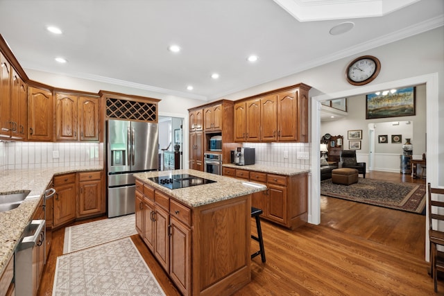 kitchen with light hardwood / wood-style flooring, backsplash, stainless steel appliances, crown molding, and a center island