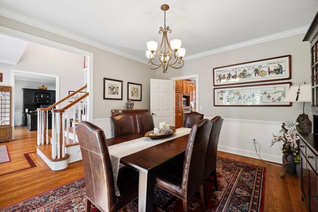 dining area featuring crown molding, an inviting chandelier, and hardwood / wood-style floors