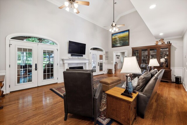 living room featuring ceiling fan, french doors, hardwood / wood-style floors, high vaulted ceiling, and ornamental molding