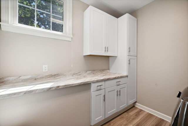 kitchen featuring white cabinets, light stone countertops, and light hardwood / wood-style floors