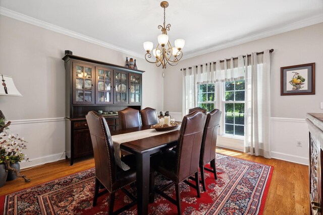 dining area featuring a notable chandelier, light hardwood / wood-style flooring, and crown molding