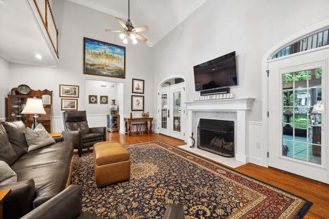 living room featuring french doors, hardwood / wood-style flooring, a premium fireplace, high vaulted ceiling, and ceiling fan