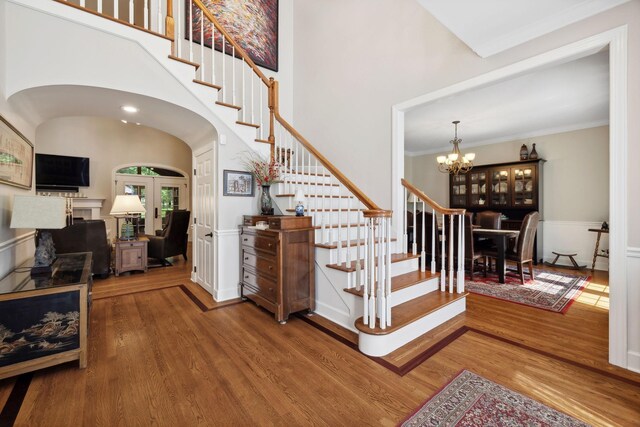 stairway featuring a notable chandelier, ornamental molding, hardwood / wood-style flooring, and french doors