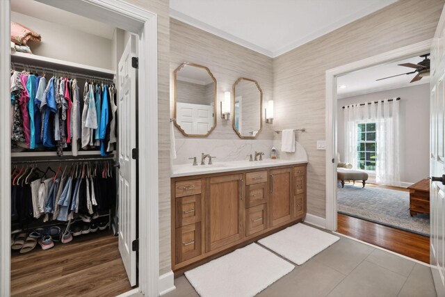 bathroom featuring tile floors, ornamental molding, ceiling fan, and dual bowl vanity