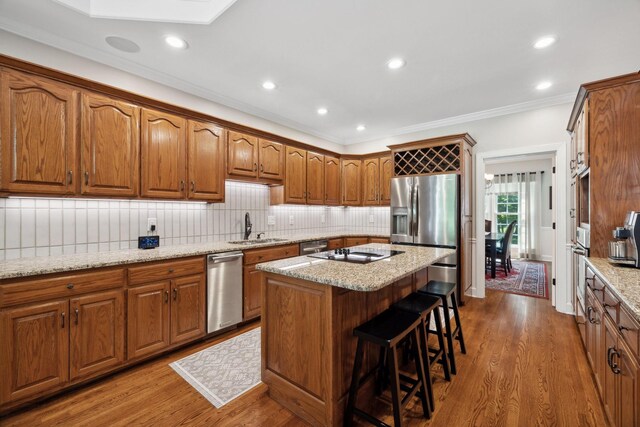 kitchen with stainless steel appliances, hardwood / wood-style floors, sink, and backsplash