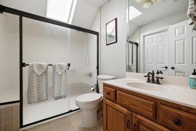 bathroom with a skylight, toilet, tile floors, walk in shower, and vanity