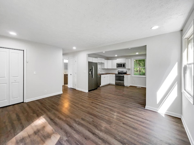 unfurnished living room featuring a textured ceiling, dark hardwood / wood-style flooring, and sink