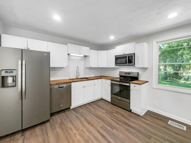 kitchen with wood counters, white cabinetry, sink, and appliances with stainless steel finishes