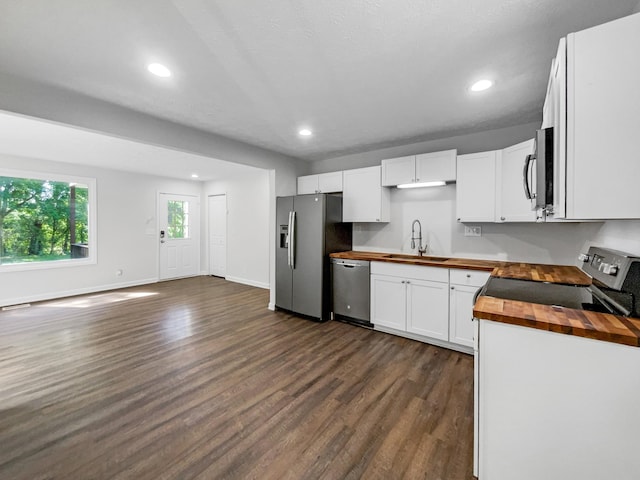 kitchen featuring butcher block counters, sink, dark hardwood / wood-style floors, appliances with stainless steel finishes, and white cabinetry