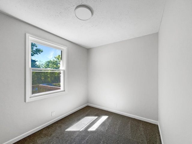 spare room featuring a textured ceiling and dark carpet