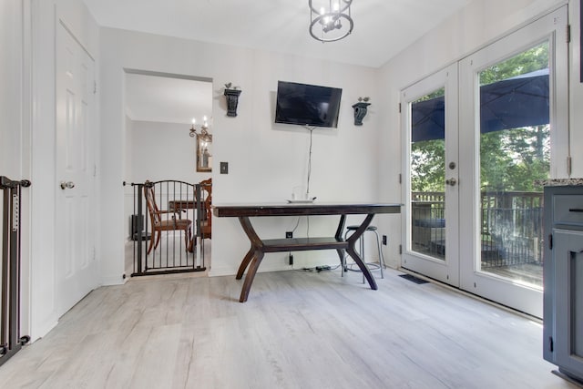 office with light hardwood / wood-style floors and a notable chandelier