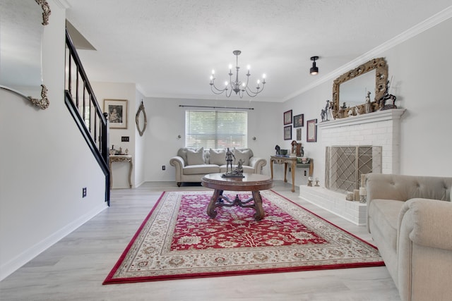 living room featuring light wood-type flooring, a brick fireplace, ornamental molding, a textured ceiling, and an inviting chandelier