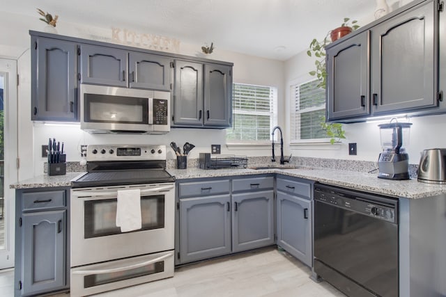 kitchen with sink, appliances with stainless steel finishes, light hardwood / wood-style floors, and gray cabinets