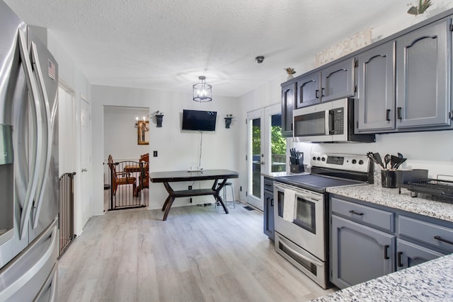 kitchen featuring light hardwood / wood-style floors, appliances with stainless steel finishes, a textured ceiling, and gray cabinetry