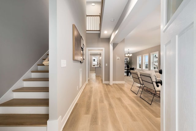 foyer entrance with a chandelier, light wood-type flooring, and a high ceiling