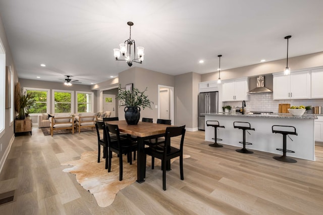 dining space featuring ceiling fan with notable chandelier and light hardwood / wood-style flooring