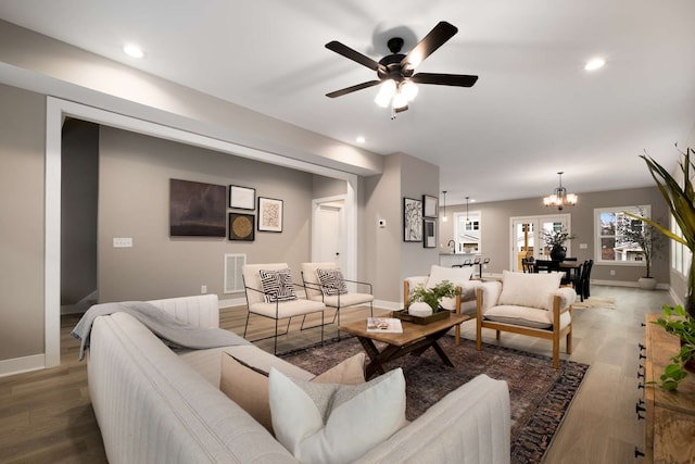 living room featuring ceiling fan with notable chandelier and hardwood / wood-style floors