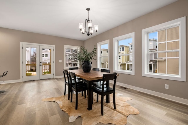 dining space featuring a healthy amount of sunlight, light hardwood / wood-style flooring, and an inviting chandelier