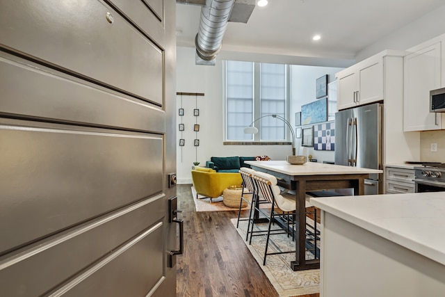 kitchen with appliances with stainless steel finishes, white cabinetry, and dark hardwood / wood-style floors