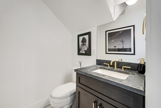 bathroom featuring vaulted ceiling, toilet, and vanity with extensive cabinet space