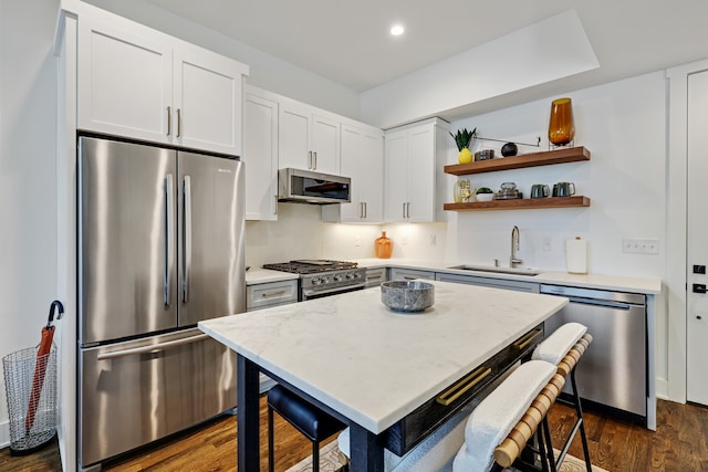 kitchen with dark hardwood / wood-style flooring, a breakfast bar area, white cabinetry, appliances with stainless steel finishes, and sink