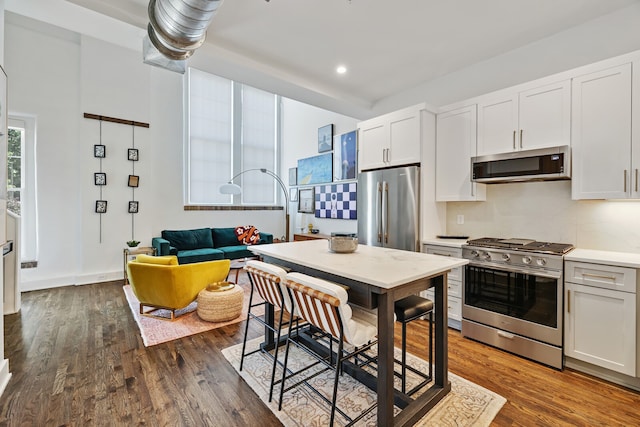 kitchen with white cabinets, appliances with stainless steel finishes, and dark hardwood / wood-style floors