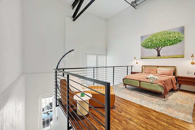 bedroom featuring wood-type flooring and a high ceiling