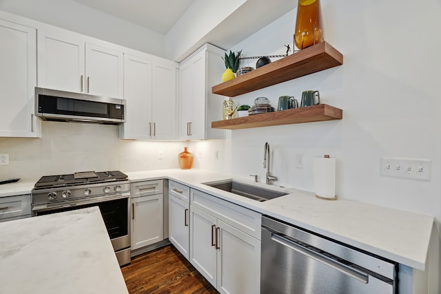 kitchen featuring light stone countertops, stainless steel appliances, dark wood-type flooring, sink, and white cabinetry