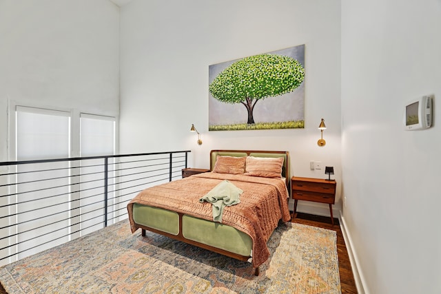 bedroom featuring dark hardwood / wood-style flooring and a high ceiling