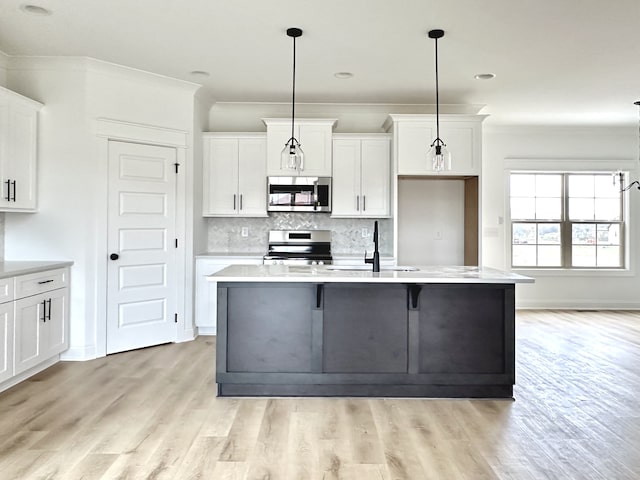 kitchen featuring white cabinetry, a kitchen island with sink, decorative light fixtures, and appliances with stainless steel finishes