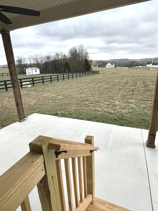 deck with a rural view, ceiling fan, and a patio area