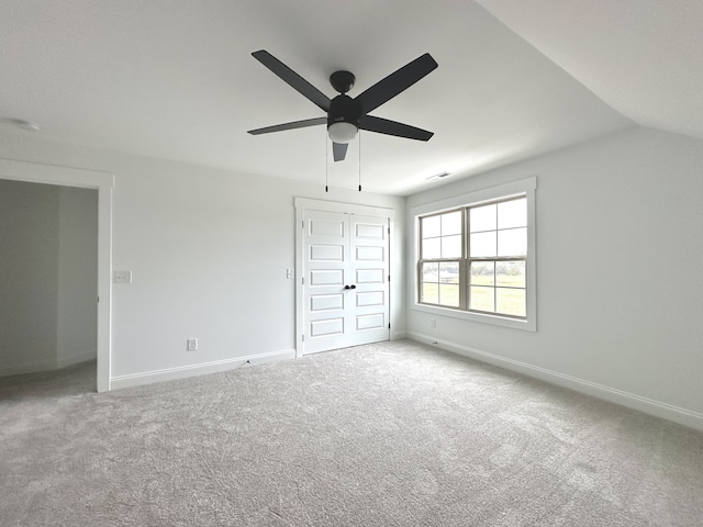 unfurnished bedroom with carpet flooring, ceiling fan, a closet, and vaulted ceiling