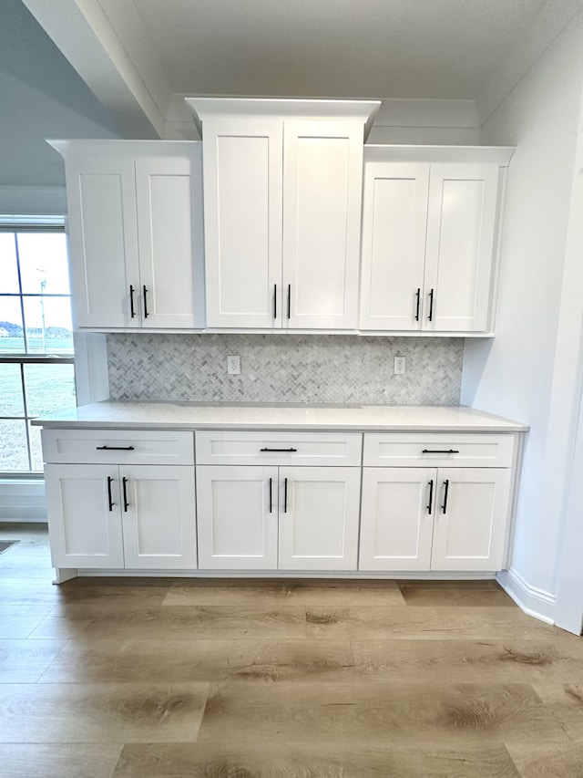 bar featuring white cabinets, light hardwood / wood-style floors, and tasteful backsplash